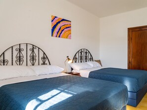 Une chambre avec deux lits, une armoire en bois et un tableau coloré accroché au mur.