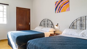 A room with two beds, a wooden door, a colorful painting, and a window. - Casa Tita penthouse with rooftop in downtown Querétaro (Santiago de Querétaro)