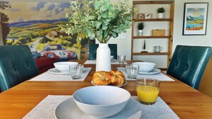 A dining table set with a bowl, croissants, and a glass of orange juice. - Stone & Vines | 2BR Wine Country Retreat | Adventure by Day, Wine by Night (Naramata)