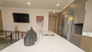 A modern kitchen with a large island, stainless steel appliances, and a flat-screen TV mounted on the wall. - Central Apartment | Downtown Zapopan (Zapopan)