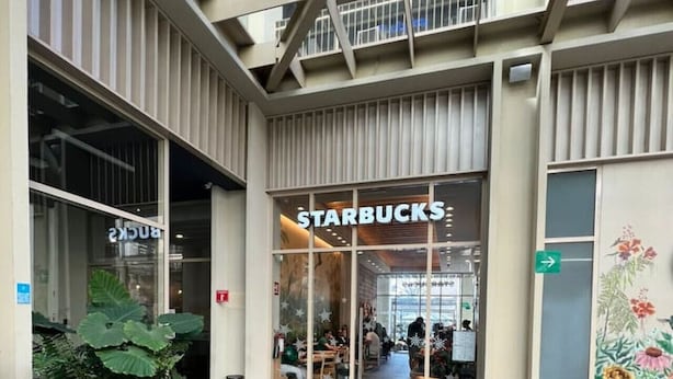 A Starbucks with a modern architectural design, featuring a glass facade and outdoor seating area with orange chairs. - Central Apartment | Downtown Zapopan (Zapopan)