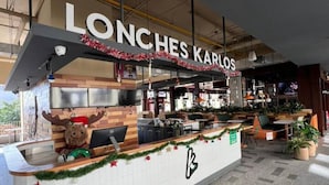 A restaurant named 'LONCHES KARLOS' with a festive decoration, a counter with a moose figure, and a tiled floor. - Central Apartment | Downtown Zapopan (Zapopan)
