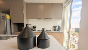 A modern kitchen with two black kitchen scales on the counter, a stainless steel refrigerator, and a window with a city view. - Central Apartment | Downtown Zapopan (Zapopan)