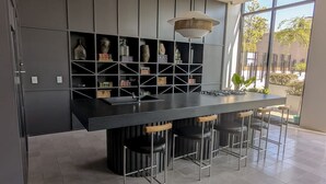 Una cucina moderna con una grande isola, sgabelli da bar e una libreria a incasso decorata con oggetti ornamentali.