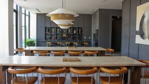 Un'elegante sala da pranzo con un tavolo lungo e diverse sedie, una lampada a sospensione e una libreria sullo sfondo.
