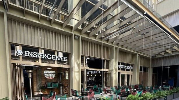 An outdoor seating area with a modern design, featuring a mix of metal and wooden furniture, and potted plants. - Nuevo+Zapopan Centro+ Cerca Basílica + Andares + (Zapopan)