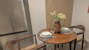A dining area with a round wooden table, four wooden chairs, a vase with flowers, and a glass of water. - Nuevo+Zapopan Centro+ Cerca Basílica + Andares + (Zapopan)