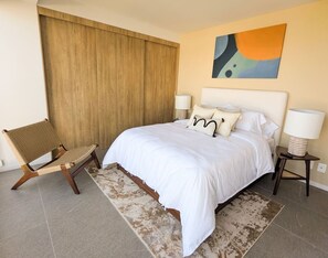 A bedroom with a large bed, a wooden chair, a rug, and a painting on the wall. - Zapopan Centro+ Cerca Basílica + Andares + Telmex (Zapopan)