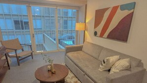 A living room with a sofa, a round coffee table, and a chair. There is a large window with a view of buildings. - Zapopan Centro+ Cerca Basílica + Andares + Telmex. (Zapopan)