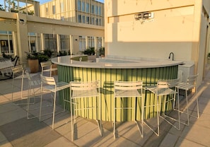 An outdoor bar area with a circular counter, four white metal chairs, and a green metal railing. - Zapopan Centro +Cerca Basílica + Andares + Telmex (Zapopan)