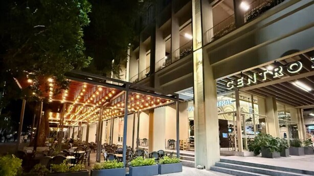 Un espace extérieur aménagé avec des tables et des chaises, une terrasse couverte et une entrée de bâtiment avec une enseigne.