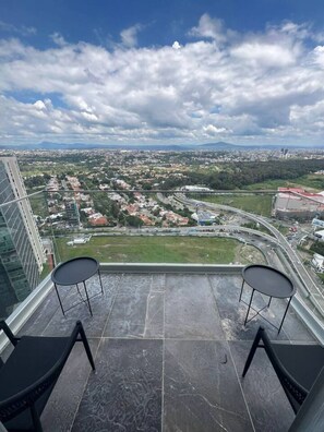 A high-rise balcony with two black chairs and a view of a cityscape, including a highway and distant mountains. - Moderno Dpt Nuevo Lobby 33 Zona Exclusiva Andares (Zapopan)