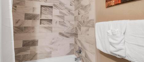 A bathroom with a shower, a bathtub, and a towel rack.