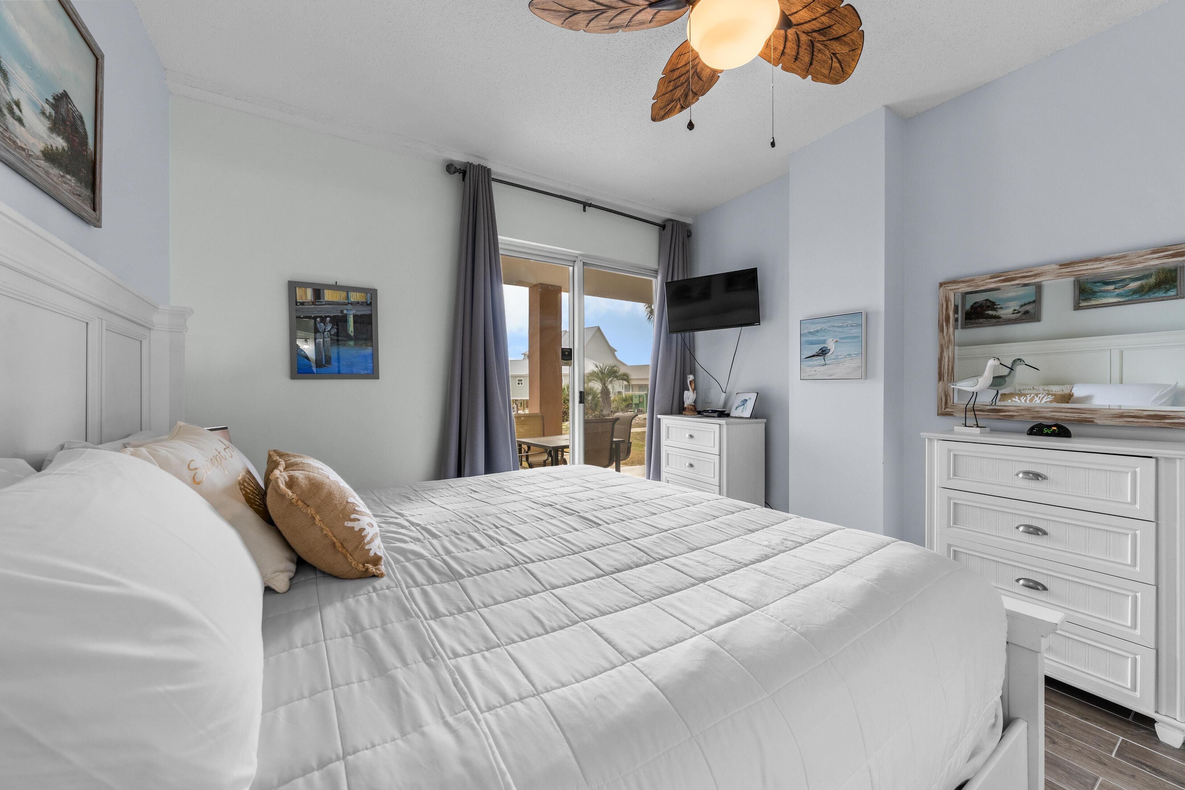 Un dormitorio con una cama grande, un aparador, un televisor y vistas al exterior.