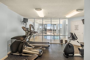 A gym with treadmills, a stationary bike, and a pool area visible through glass doors.