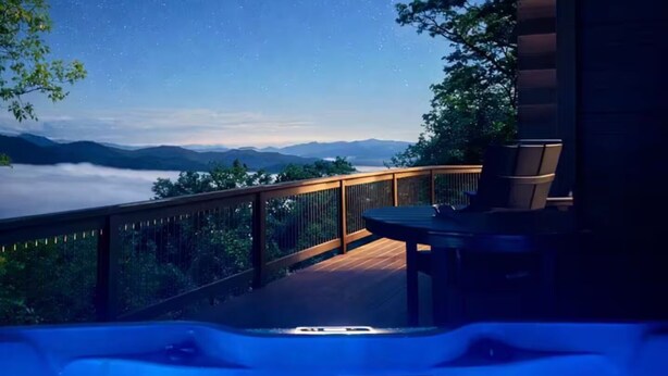 Eine Terrasse mit Whirlpool und Blick auf die Berge unter einem Sternenhimmel.