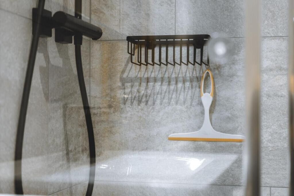 A bathroom with a shower, a towel rack, and a glass door.