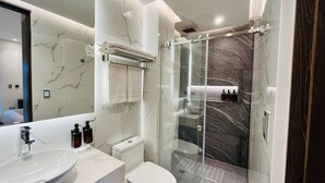 A modern bathroom with a glass-enclosed shower, a white sink, and a toilet. - Hotel Murahno (San Jose de Cucuta)