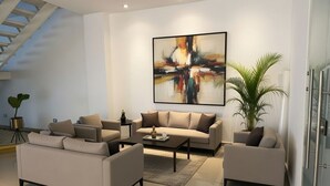 A modern living room with a sofa set, a coffee table, and a large abstract painting on the wall. - Hotel Murahno (San Jose de Cucuta)