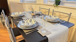A dining table set with blue and white patterned plates, clear wine glasses, and silverware. - Spacious 2-Bedroom Duplex with Gated Parking (Doncaster)