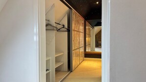 A modern walk-in closet with sliding doors, a hanging rod, and built-in shelves. - Spacious 2-Bedroom Duplex with Gated Parking (Doncaster)