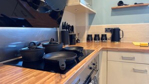 A kitchen with a black induction cooktop, four black pots, and a coffee maker on the counter. - Stylish 2-Bedrooms | Free Gated Parking | 2 Bathrooms (Doncaster)