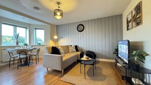 A living room with a sofa, coffee table, TV, and a dining area with chairs and a table. - Stylish 2-Bedrooms | Free Gated Parking | 2 Bathrooms (Doncaster)