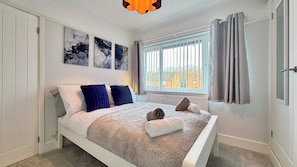 Ein Schlafzimmer mit Bett, weißen Wänden und einem fenster mit Vorhängen.