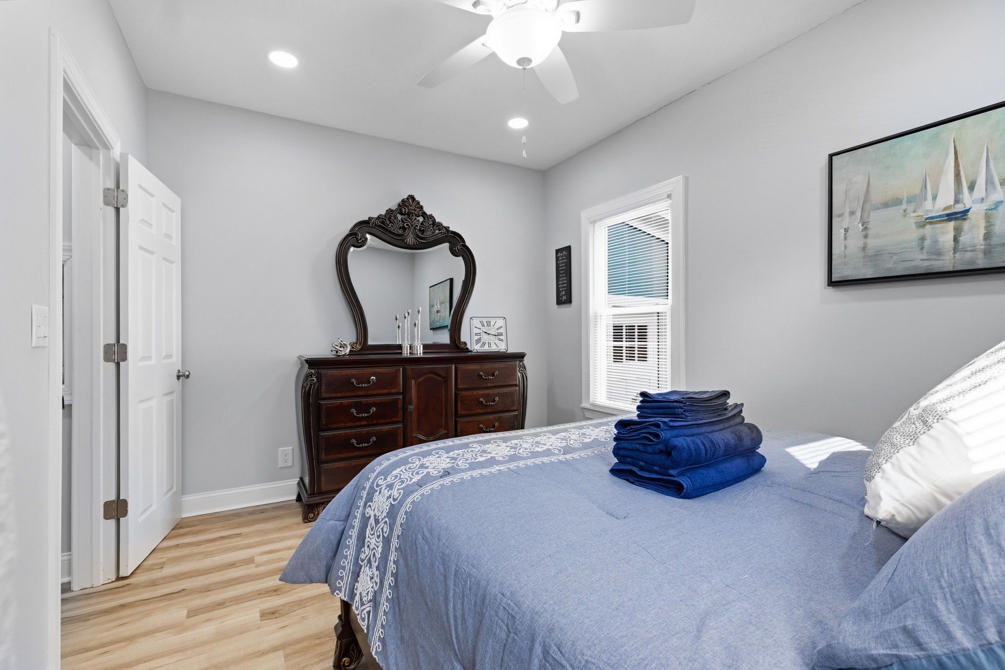 A bedroom with a bed, dresser, and a ceiling fan.