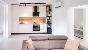 Une cuisine moderne avec des armoires blanches, un four encastré et une hotte noire.