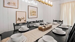 A dining room with a long table set for six, framed artwork on the walls, and a modern chandelier. - Cozy Cottage Mountain Retreat | The Glade Escape (Gatlinburg)