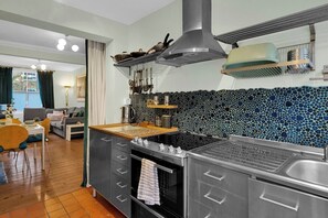A modern kitchen with a central island, a built-in oven, and a backsplash with a mosaic pattern. - Stylish 2BR House near Canary Wharf & Docklands (Greater London)