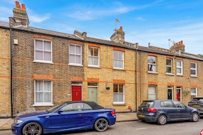 A row of terraced houses with a blue car parked in front. - Stylish 2BR House near Canary Wharf & Docklands (Greater London)