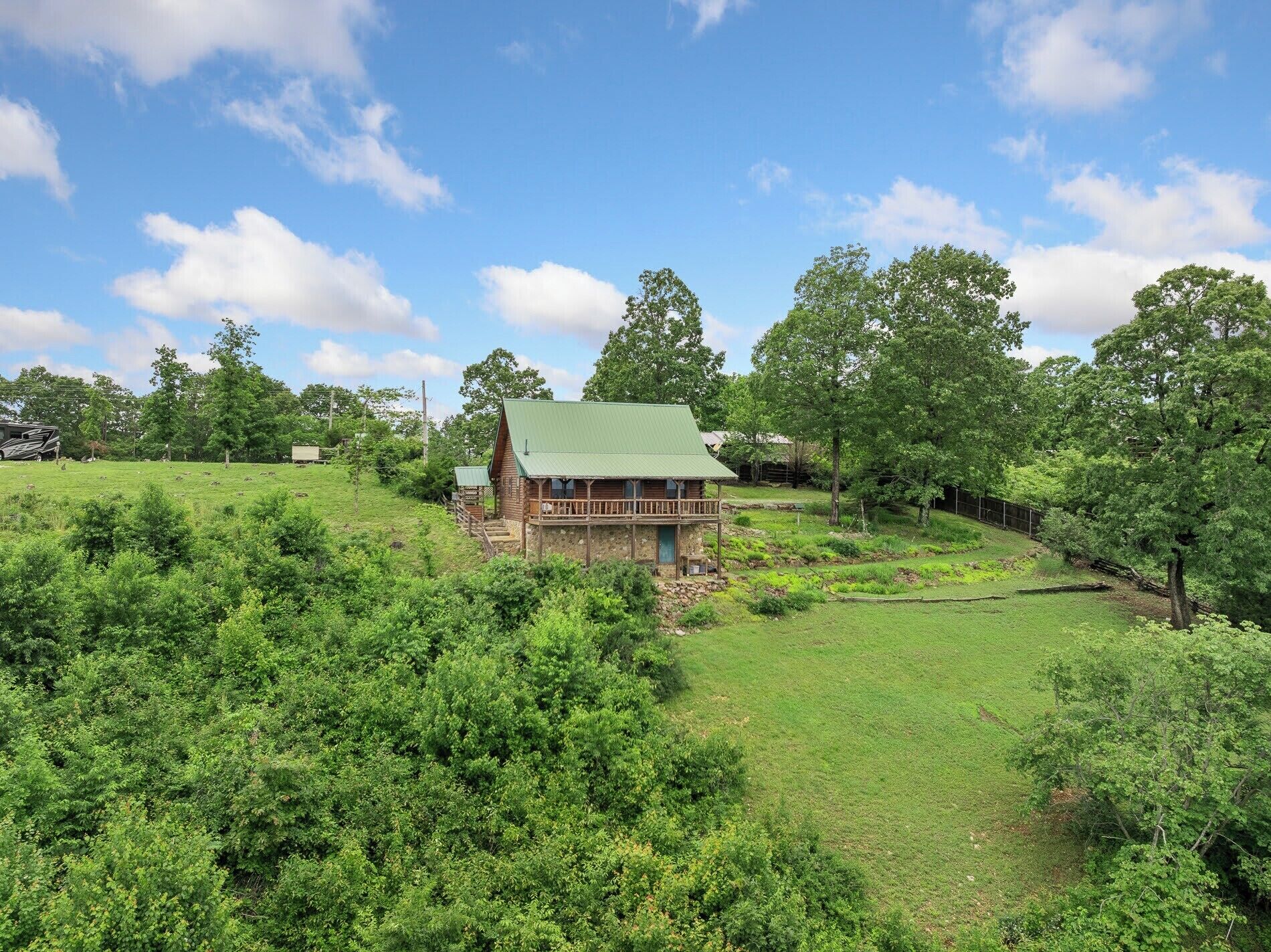 A rustic cabin with a green roof, surrounded by lush greenery and trees.