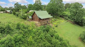 A rustic cabin with a green roof, surrounded by lush greenery and trees. - Rustic Cedar Roost • Private Balcony • Best Views (Jasper)