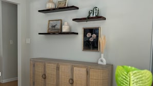Um quarto com um armário de madeira, estantes com objetos decorativos e um vaso de planta.