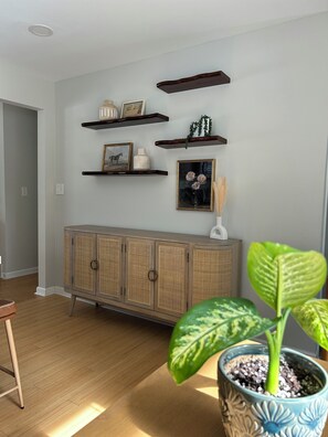 A room with a wooden cabinet, shelves with decorative items, and a potted plant. - Mid-Century Modern Themed Ranch-Styled Surprise House (Delafield)