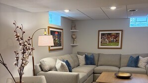 Sala de estar com uma mesa de madeira redonda, um sofá, uma mesa de centro e obras de arte nas paredes.
