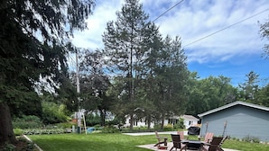 Um quintal bem cuidado com gramado, área de churrasco e um galpão.
