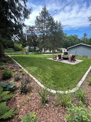 A well-maintained backyard with a lawn, a barbecue area, and a shed. - Mid-Century Modern Themed Ranch-Styled Surprise House (Delafield)