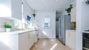 Une cuisine moderne avec des meubles blancs, un îlot central et une vue à travers une fenêtre en arc de cercle.