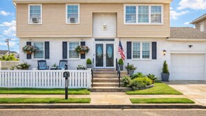 A two-story house with a front porch, a mailbox, and a flag. - 5BR Beach House in WW Crest - Sleep 12! (Wildwood)