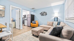 A modern living room with a sofa set, a dining area with chairs, and a kitchen in the background. - North WW 3BR Cottage Near Beach, Family-Friendly! (Wildwood)