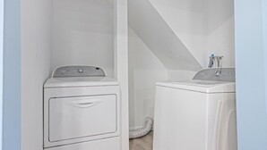 A laundry room with two white front-loading washing machines and a hose running from one of them. - North WW 3BR 1st Floor - Steps to the Beach! (North Wildwood)