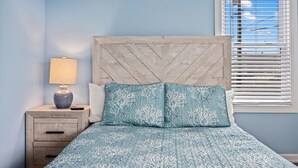 A bedroom with a bed, nightstand, lamp, and window with blinds. - North WW 3BR 1st Floor - Steps to the Beach! (North Wildwood)