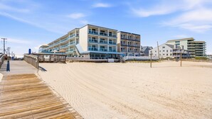 Un hotel sulla spiaggia con numerosi balconi, una passerella in legno e una spiaggia sabbiosa.