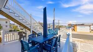 Een balkon met blauw meubilair, een witte balustrade en uitzicht op de straat en gebouwen.