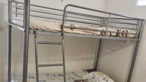 Een stapelbed met een ladder, een bloemenbedovertrek en een kussen op het onderbed.
