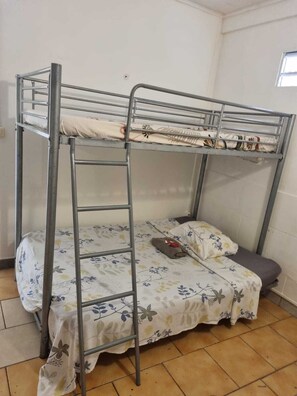 A bunk bed with a ladder, a floral bedspread, and a pillow on the lower bunk. - Progress House (Fort-de-France)