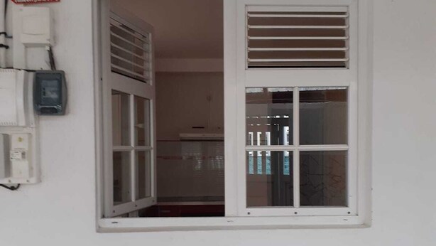 Een wit gebouw met een raam en een witte omlijsting en ventilatie.